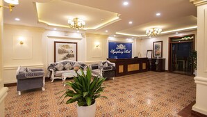 A hotel lobby with a reception desk, sofas, and a large potted plant. - Sapa Symphony Hotel (Sa Pa)