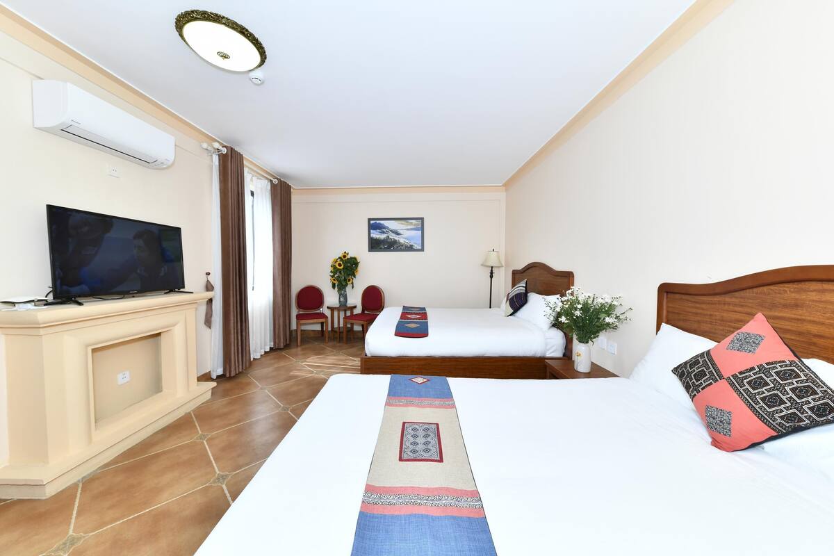 Una habitación de hotel con una cama, televisión, escritorio y silla.