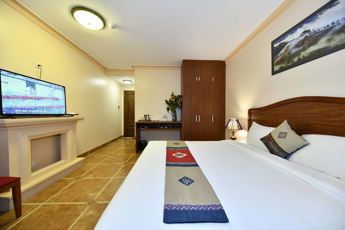 Una habitación de hotel con cama, televisión, escritorio y armario.