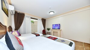 A hotel room with two beds, a television, a small table with a plant, and a window with curtains. - Sapa Symphony Hotel (Sa Pa)
