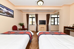 A hotel room with two beds, a TV, a desk, a chair, and a window with curtains. - Sapa Symphony Hotel (Sa Pa)
