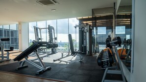 A modern gym with various exercise equipment, large windows, and a city view. - OYO Home 43995 Premium 3br 1tebrau (Johor Bahru)