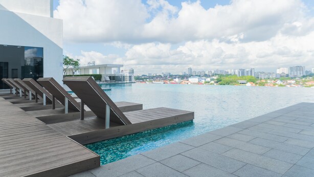 A modern pool area with sun loungers and a city view. - OYO Home 43995 Premium 3br 1tebrau (Johor Bahru)