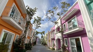 A residential street with colorful houses, a paved walkway, and trees. - Burano Yellow Villa (Hengchun)