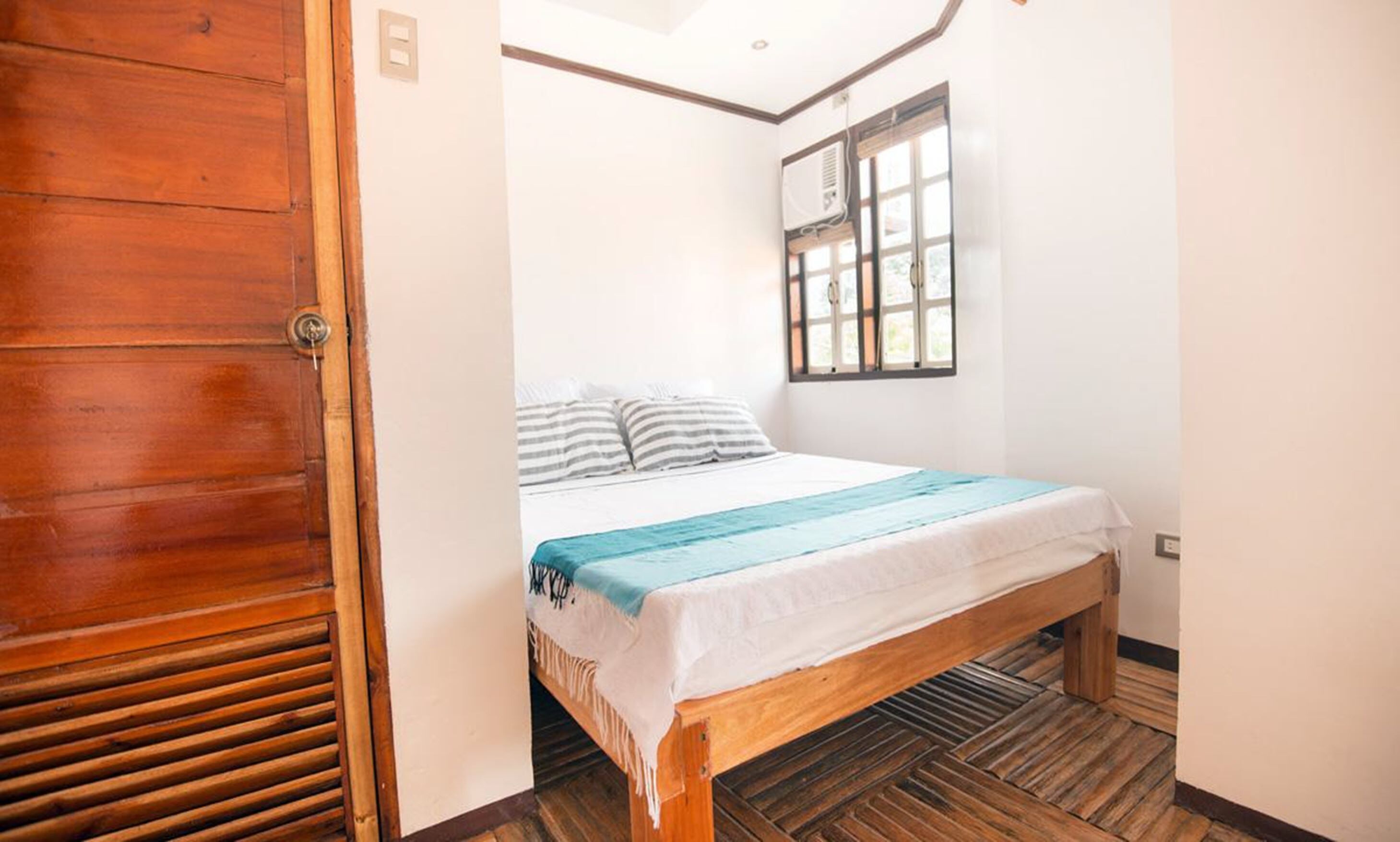Un dormitorio con una cama de madera, una ventana y una puerta.