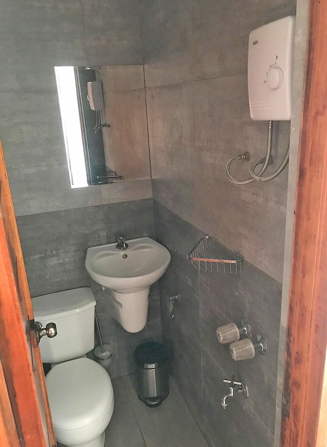 A compact bathroom with a toilet, sink, and a small mirror.