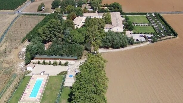 Vista aérea de una propiedad con piscina, varios edificios y campos aledaños.