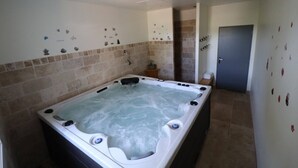 Un jacuzzi grande en una habitación con paredes de azulejos y una puerta.