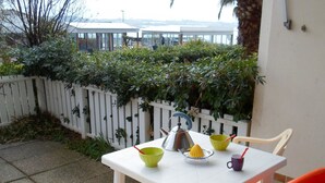 A small outdoor table with chairs, a kettle, a green bowl, and a yellow citrus squeezer.