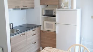 A compact kitchen with wooden cabinets, a microwave, a coffee maker, and a sink.