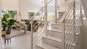A modern interior with a staircase, a living area with a sofa and chairs, and large windows. - New Luxury-Professionally Decorated Home Pool/Spa 5 Minute walk to AMI ocean (Anna Maria)