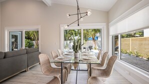 A dining area with a glass table, wicker chairs, and a modern chandelier. - New Luxury-Professionally Decorated Home Pool/Spa 5 Minute walk to AMI ocean (Anna Maria)