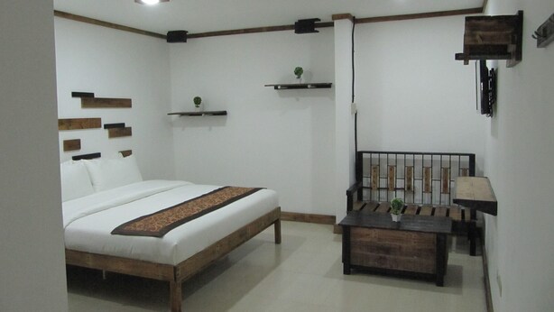 A bedroom with a bed, bedside table, and a small desk with a chair. - The Dennison Hotel (Angeles City)