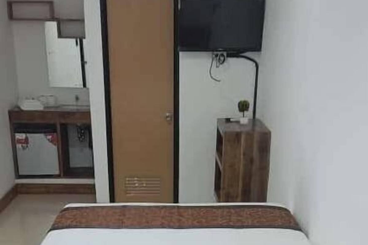 A bed with a wooden frame and white bedding in a room with a tiled floor.