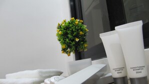 A dental kit, two conditioning shampoo bottles, and a white towel on a wooden surface. - The Dennison Hotel (Angeles City)