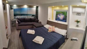 Ein modernes Hotelzimmer mit einem Bett, einer Couch, einem Gemälde und einem kleinen Tisch.