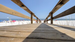 A wooden pier leading to a beach with umbrellas and beachgoers. - Beachside Cottage 2BR-3BA. Now booking for Summer! (Orange Beach)