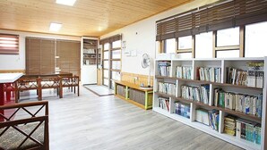 Une bibliothèque dotée de planchers en bois, d’étagères et d’un espace repas avec des tables et des chaises.