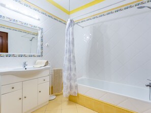 Un bagno con lavandino bianco, specchio e vasca da bagno.