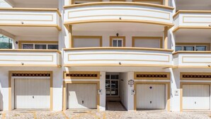A multi-story building with balconies, a central entrance, and garage doors.
