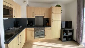 A compact kitchen with a microwave, coffee maker, oven, and a small TV.