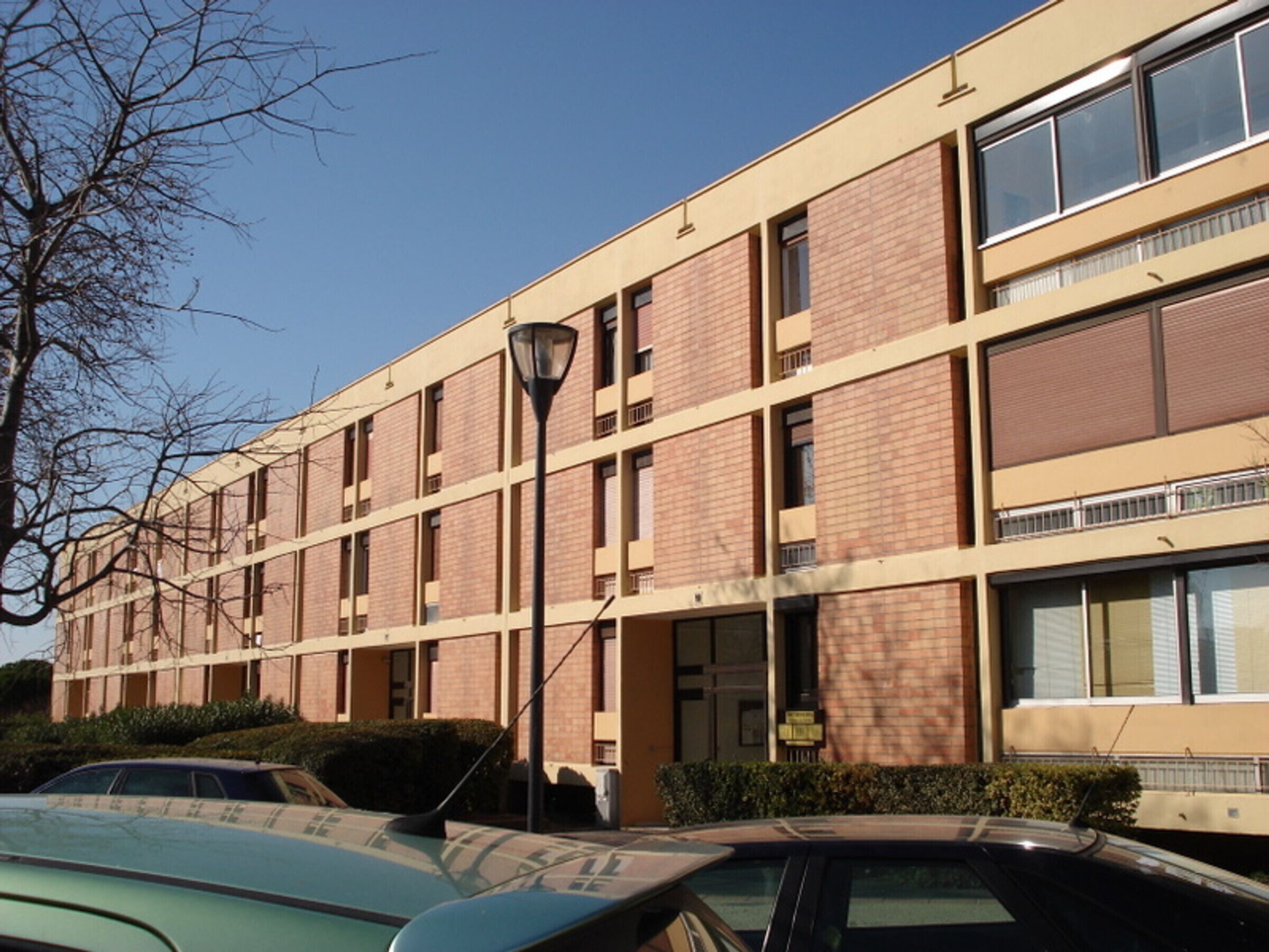 Un immeuble à plusieurs étages, doté d’une façade en briques, de grandes fenêtres et d’un toit plat.
