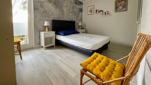 Un dormitorio con cama, mesitas de noche, una silla y vistas al exterior.
