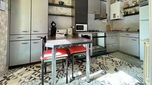 Una cocina moderna con gabinetes grises, un microondas, una cafetera y una estufa a gas. Hay dos sillas rojas junto a una pequeña mesa.