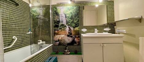 Un baño con ducha, lavabo y espejo.