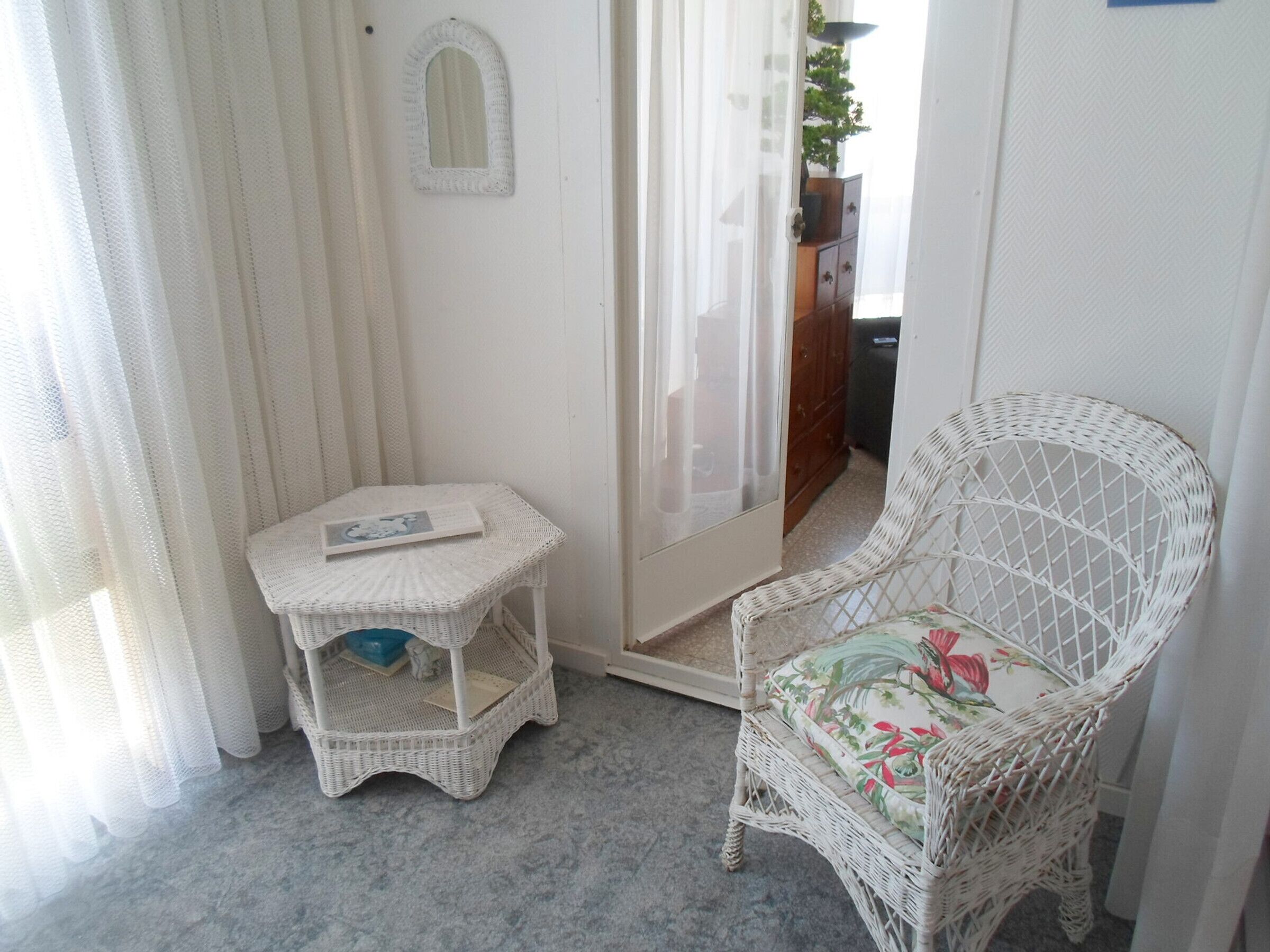 A small room with a wicker chair and a wicker table.