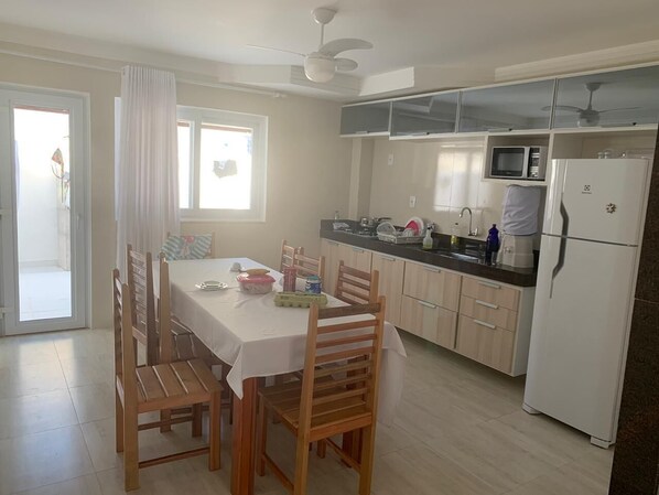 A kitchen with wooden cabinets, a white refrigerator, a microwave, and a dining table with chairs.