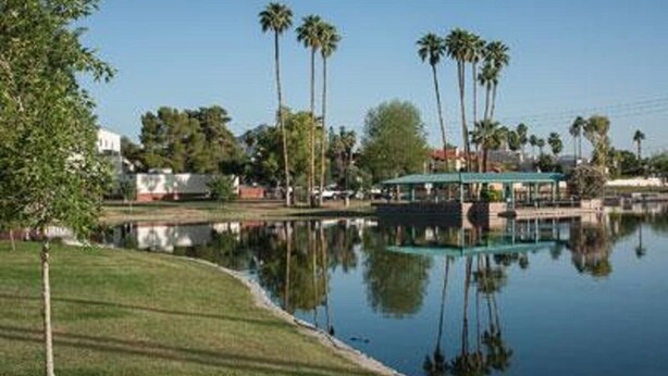 Un lac paisible, agrémenté d’un kiosque et de palmiers.