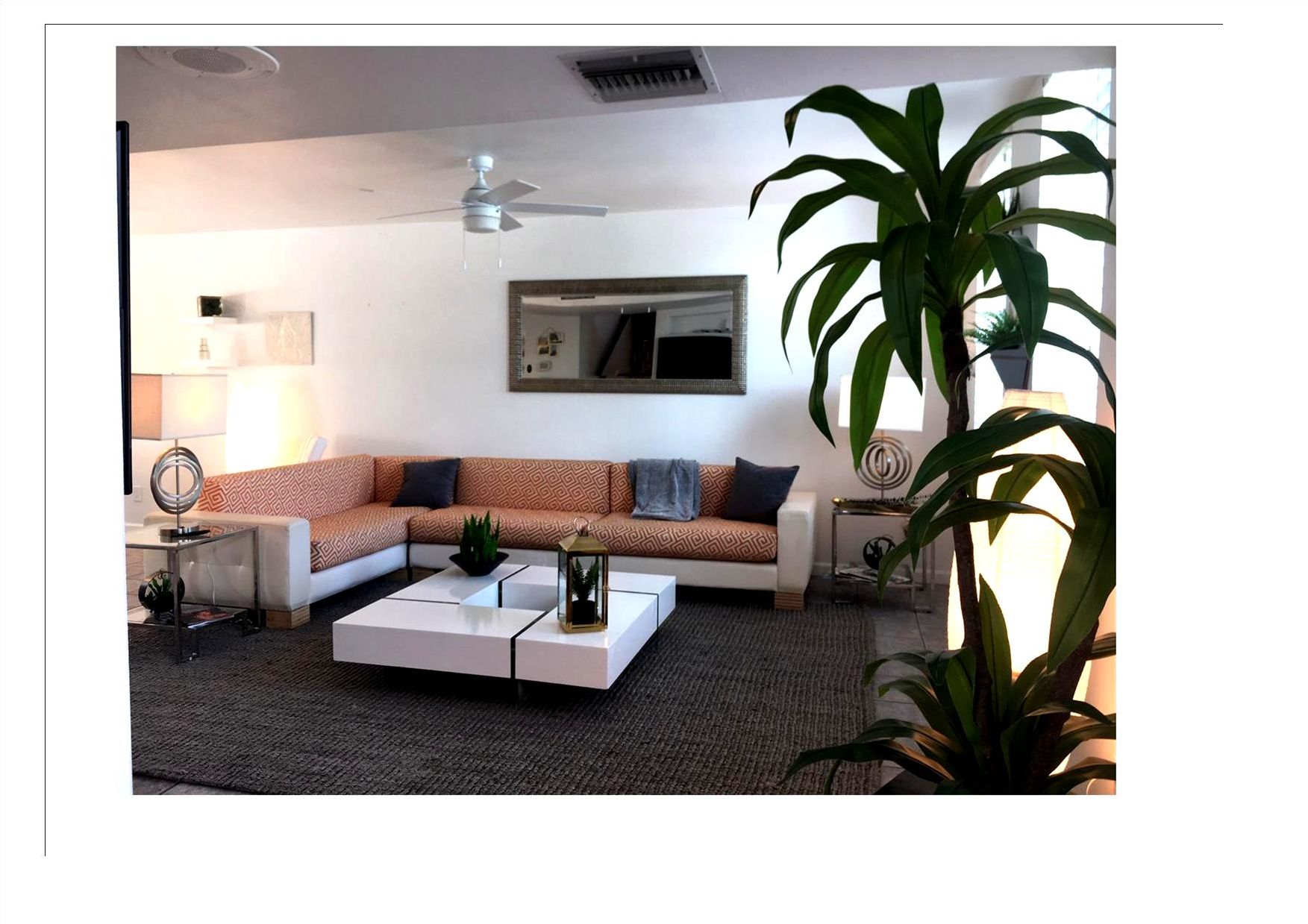 A modern living room with a sectional sofa, a coffee table, and a ceiling fan.