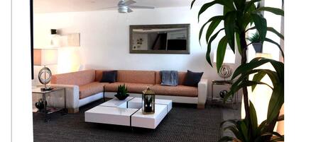 A modern living room with a sectional sofa, a coffee table, and a ceiling fan.