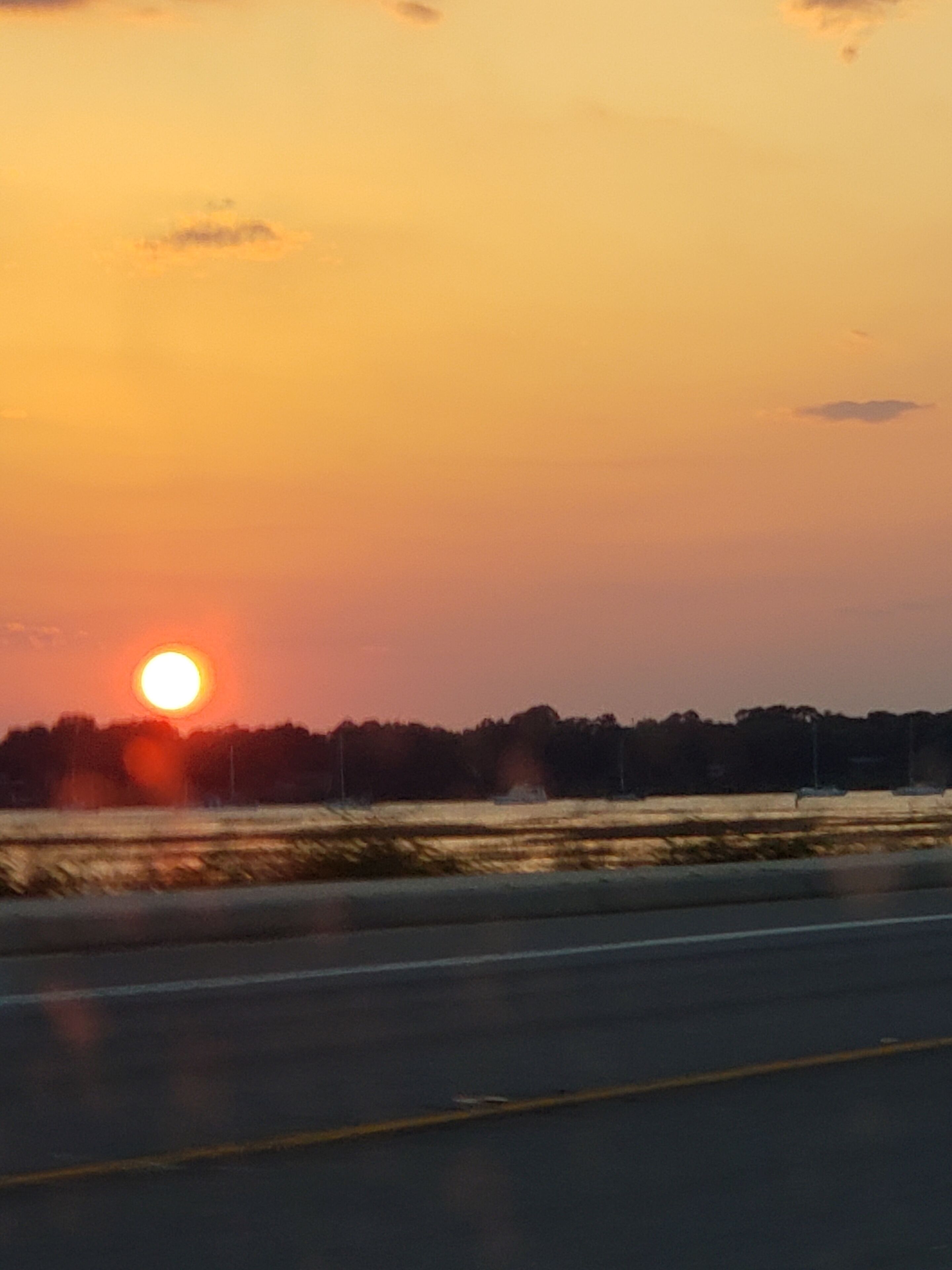 A sunset over a road with a clear sky.