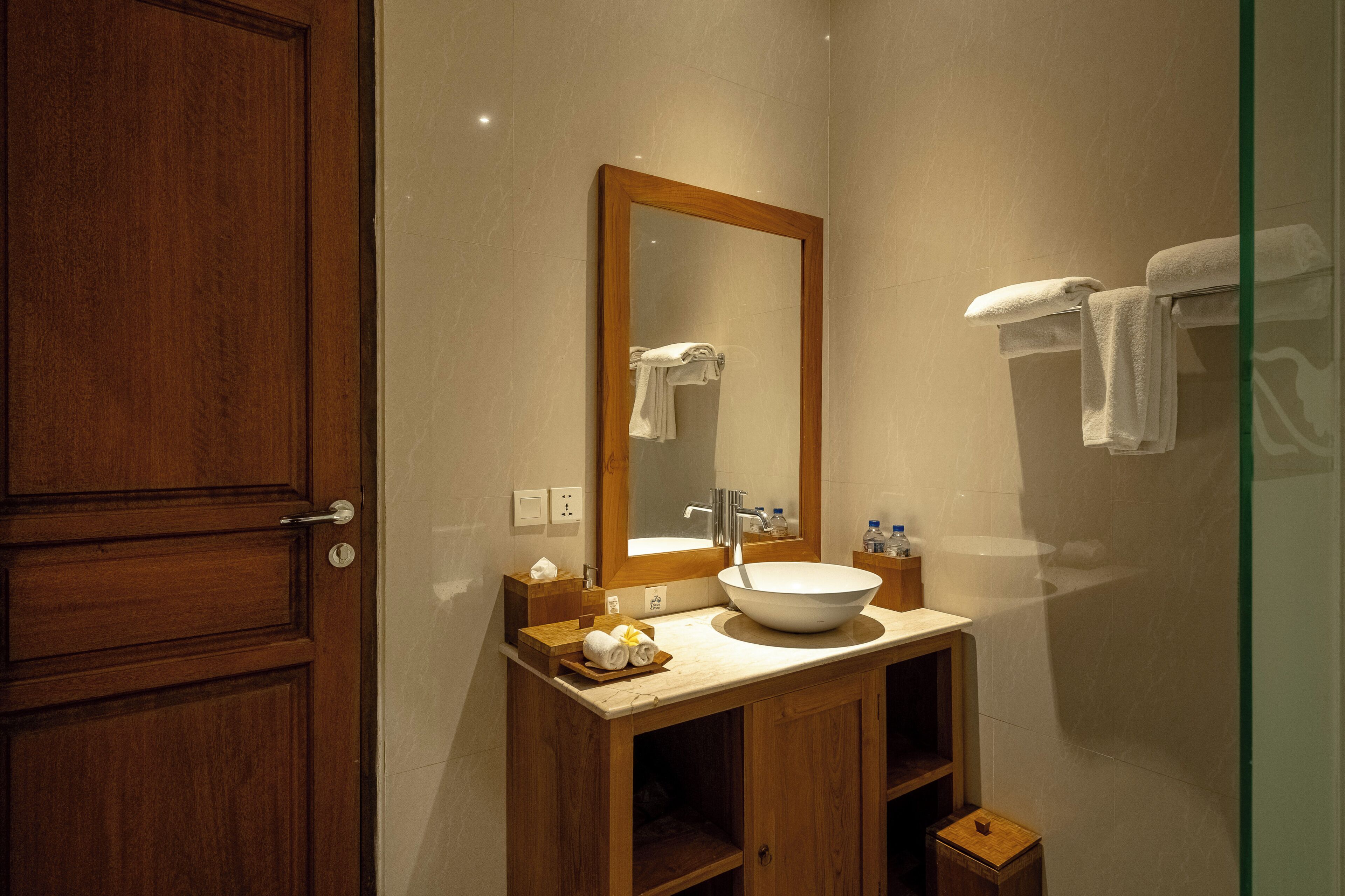 Un baño con tocador de madera, un espejo grande, un lavabo y toallas colgadas en la pared.