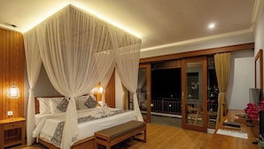 A bedroom with a four-poster bed, wooden headboard, bedside tables, a bench, and a balcony with a glass door. - Paon Desa Ubud Hotel (Ubud)