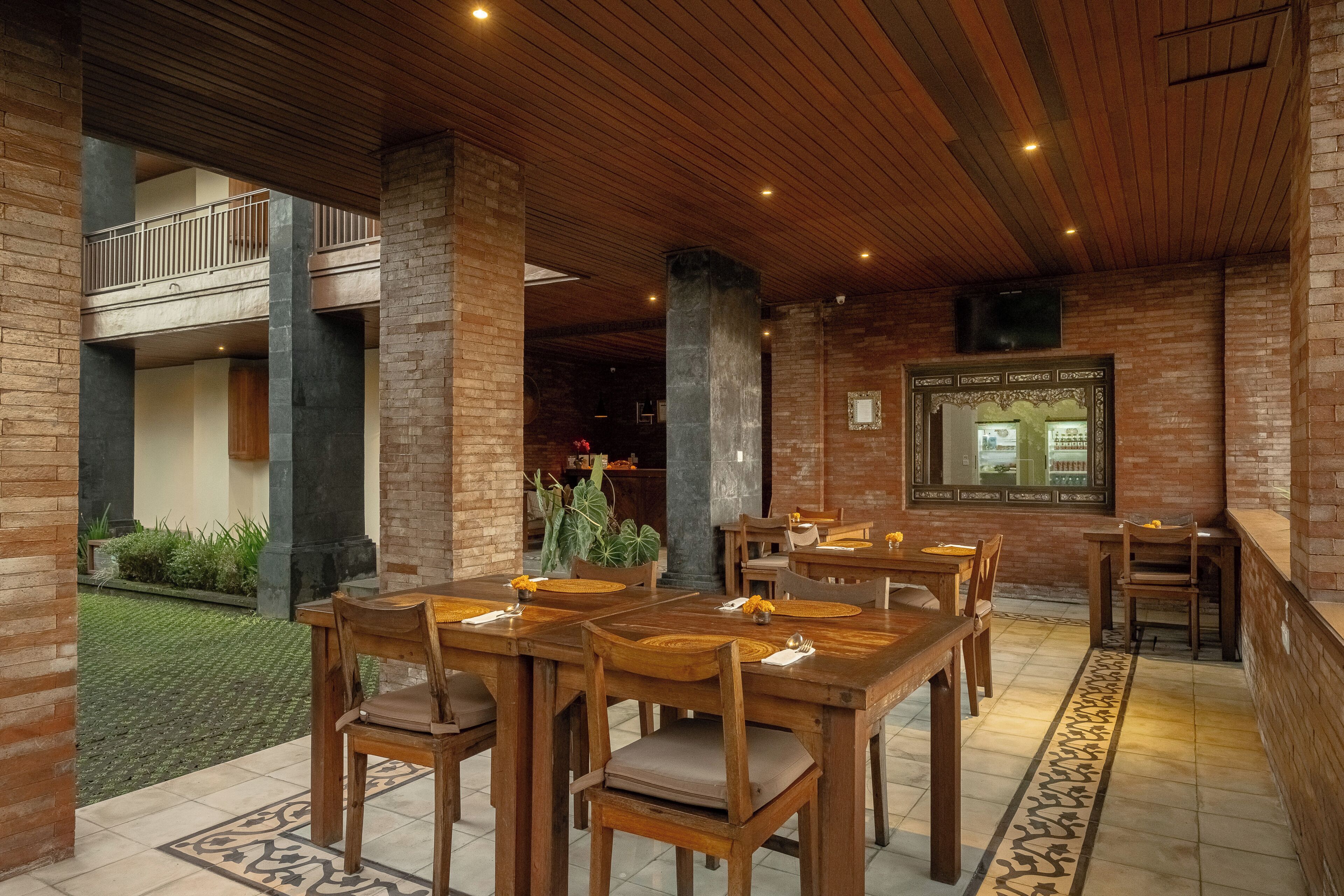 A restaurant with wooden tables and chairs, brick walls, and a balcony.