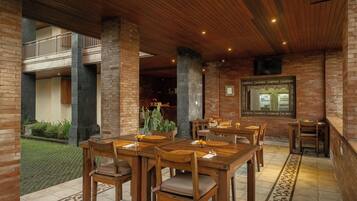 A restaurant with wooden tables and chairs, brick walls, and a balcony.