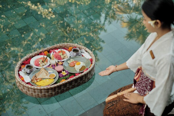 A wicker tray with various food items and a person standing beside it. - Paon Desa Ubud Hotel (Ubud)