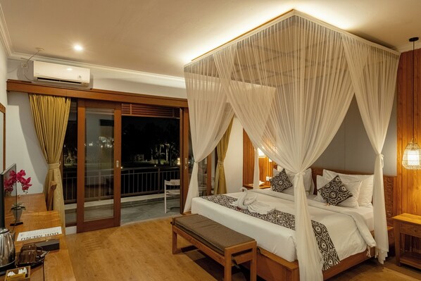 A four-poster canopy bed with a white bedspread, a wooden bench, and a nightstand with a lamp.