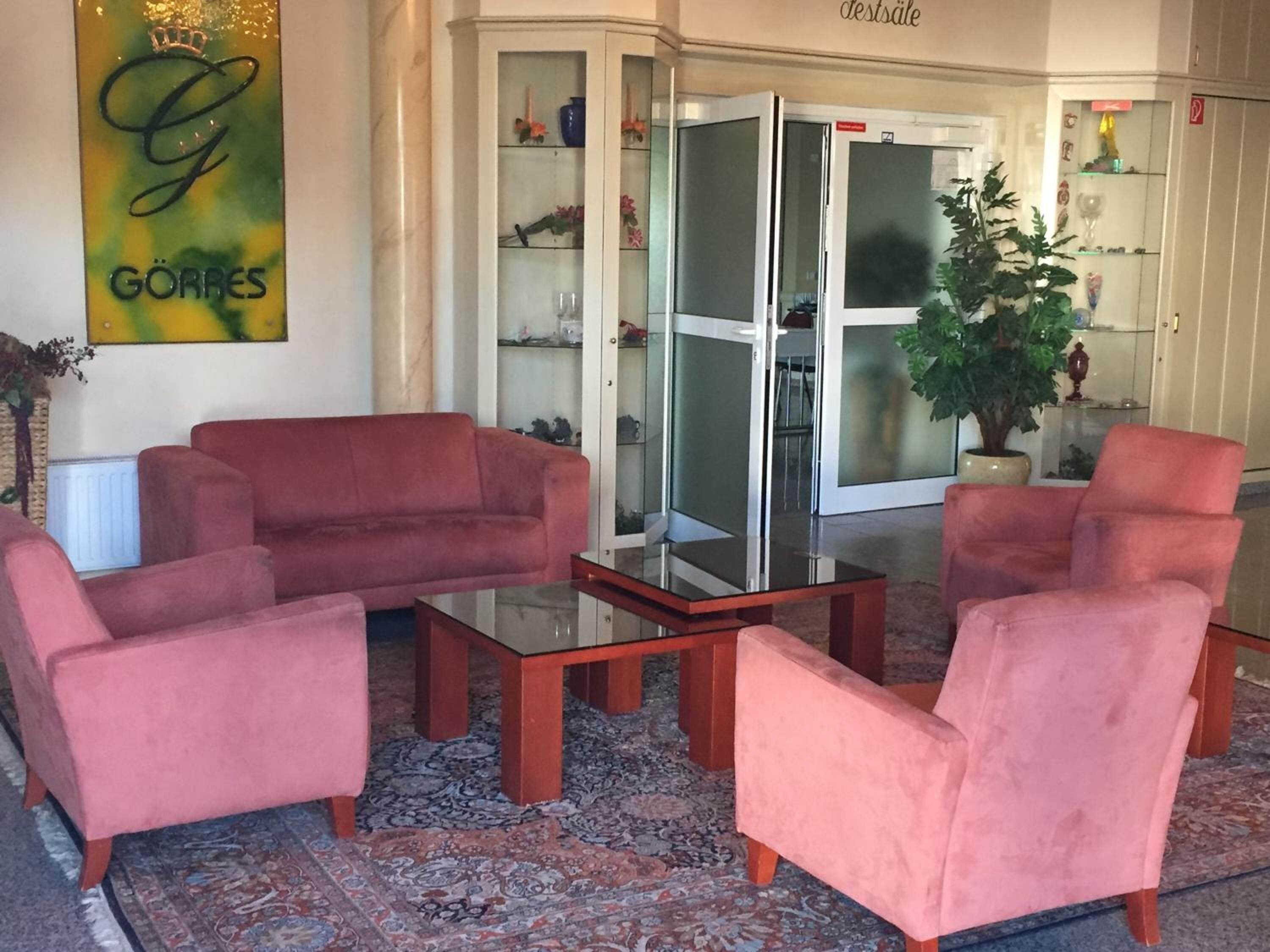 A lobby with a red sofa set, a glass coffee table, and a patterned rug.