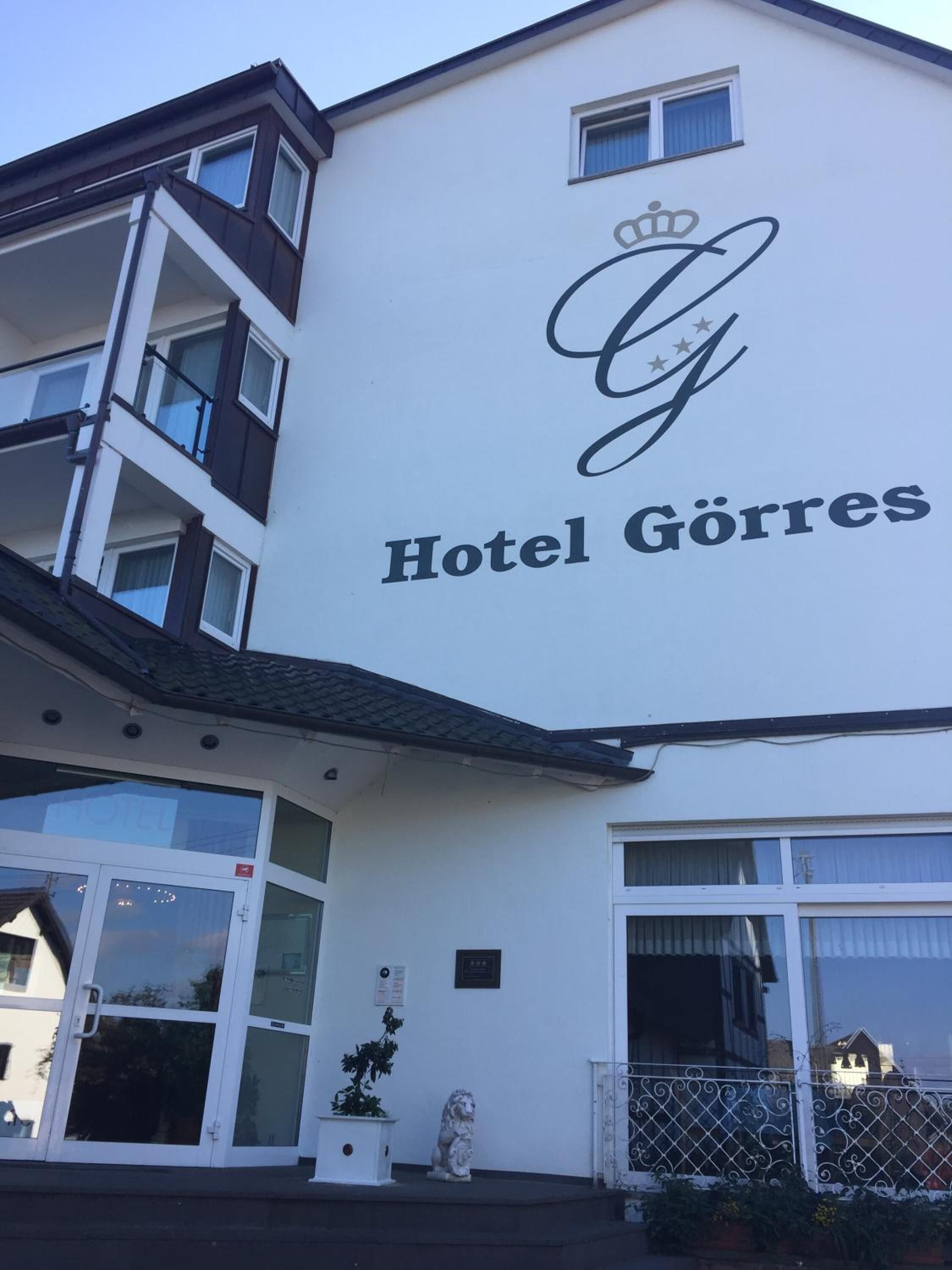 A building with a sign reading "Hotel Görres" and a lion statue in front.