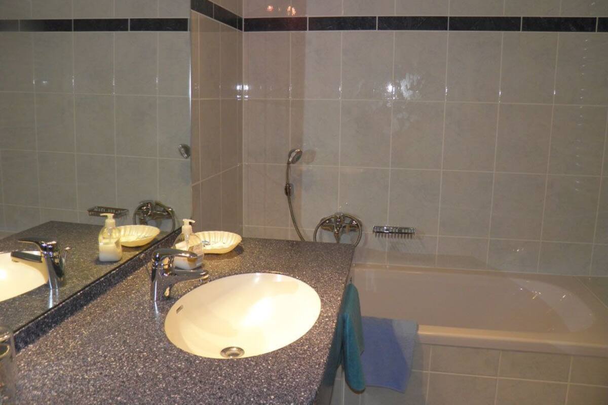 A bathroom with a sink, mirror, and bathtub.