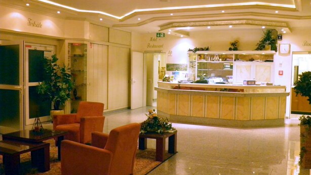 Vestíbulo de hotel con mostrador de recepción, zona de estar y kitchenette.