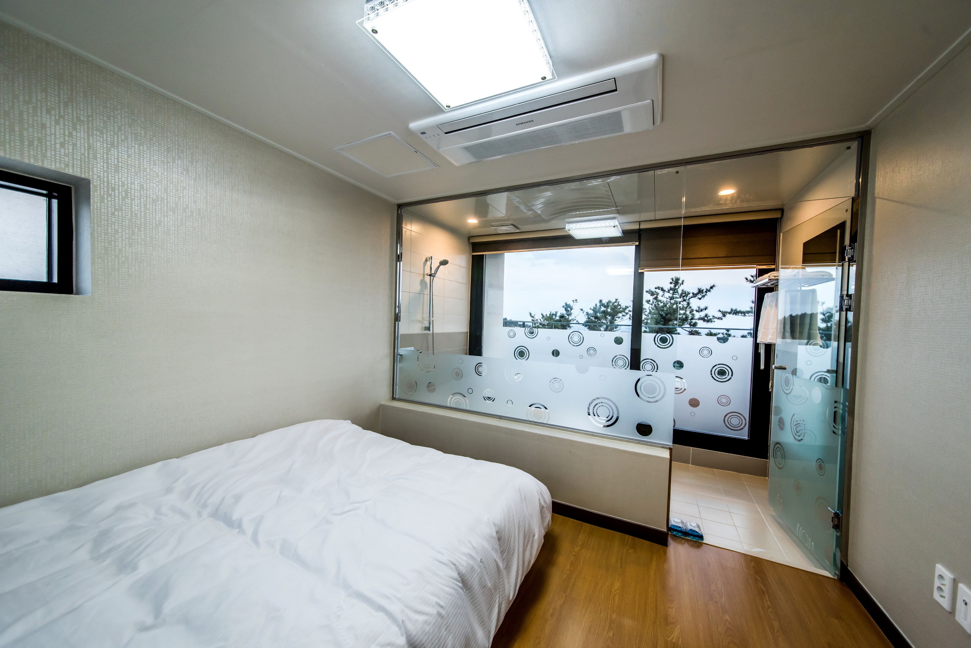 A bedroom with a bed, a window with a view, and a ceiling light.
