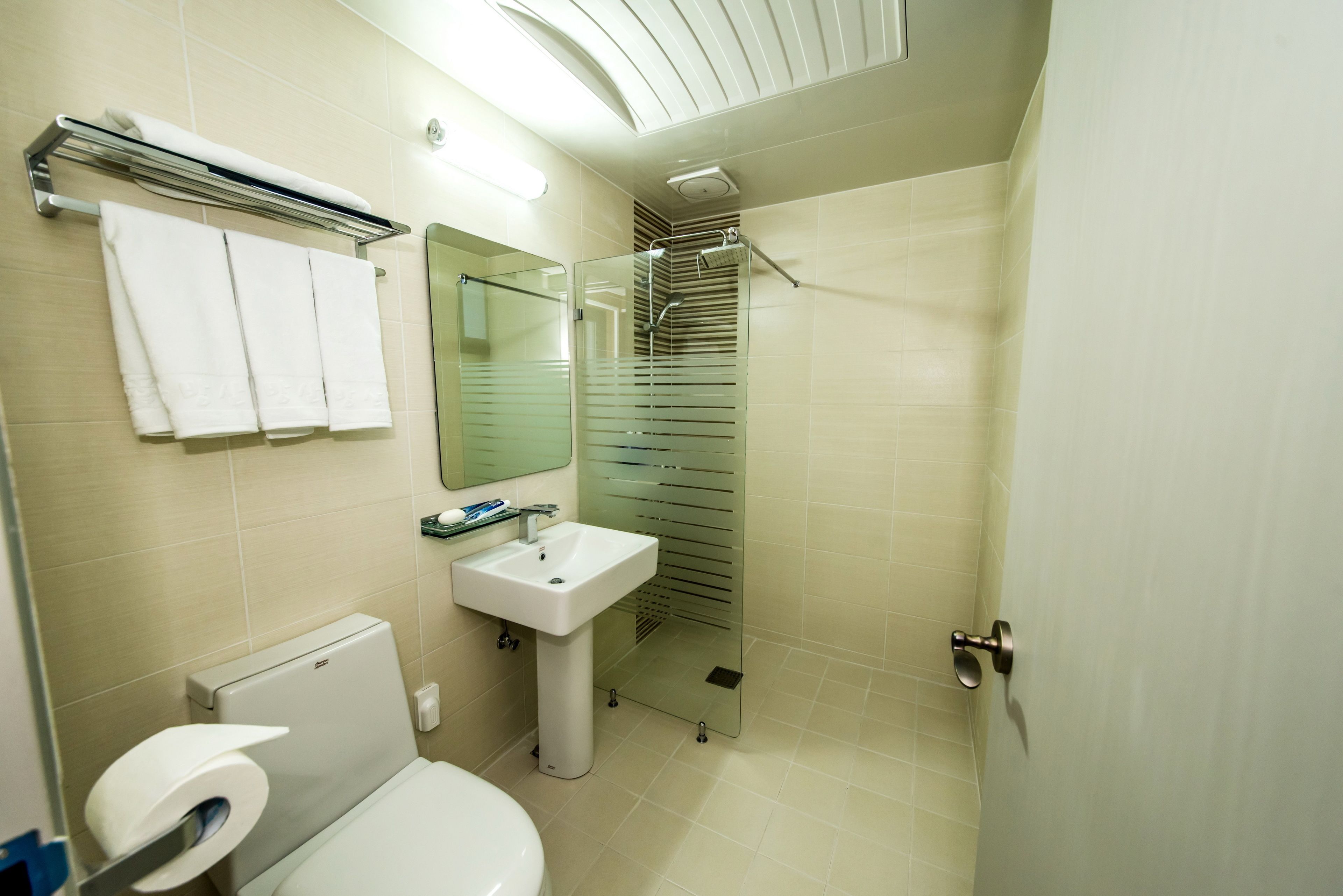 A modern bathroom with a toilet, sink, and glass shower enclosure.
