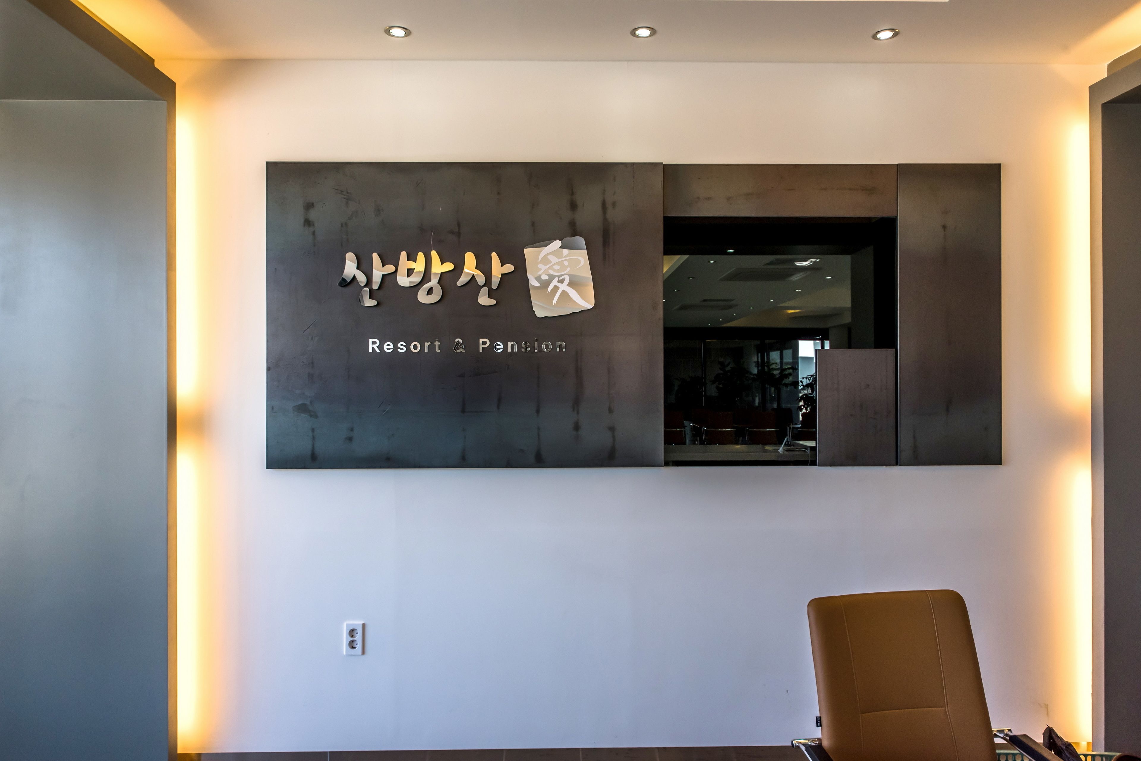 A modern interior with a wall-mounted sign reading "Resort & Pension" in Korean.