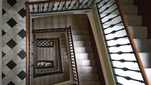 A spiral staircase with a checkered pattern on the walls and a wooden handrail. - V Barcelona Hostal (Barcelona)