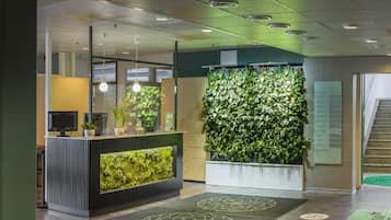A reception area with a green wall, a reception desk, and a staircase.